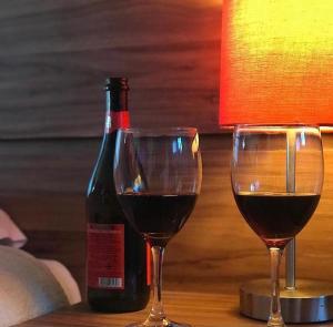 two glasses of red wine next to a bottle of wine at Suítes Hortênsias in Lavras Novas