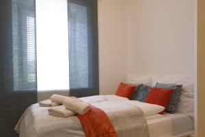a bedroom with a white bed with orange and gray pillows at Lauras Ferienwohnung - Ihre Wohlfühloase in der Südweststeiermark mit Garten, Pool, Biotop & Weinbar in Eibiswald +78 photos