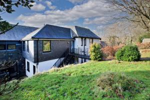 a white house with a black roof and a yard at Pinewood Lodge in South Brent
