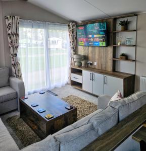 una sala de estar con un sofá y una mesa en Billing Aquadrome Holiday Park Fishing Lakes Gold Caravan, en Great Billing