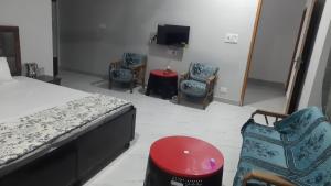 Un dormitorio con sillas y una cama y un televisor. en AAAC HoME STAY, en Sundarnagar