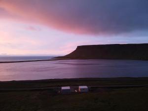 a view of a field with a lake and a mountain at Kirkjufell View Cottages in Grundarfjordur