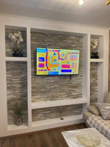 a living room with a tv on a brick wall at Maison individuelle, 3chambres, avec parking in Le Grand-Quevilly