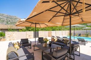a patio with chairs and an umbrella and a pool at Villa MarLea in Dubrovnik