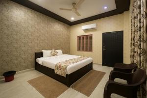 a bedroom with a bed and a chair in it at HOTEL SHIVAYY MAJESTIC - BHU Sundarpur Road 3km from KASHI VISHWANATH TEMPLE in Varanasi