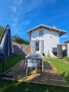 a table and an umbrella on a deck with a house at Maison T2 avec jardin à Bidart proche de toutes commodités in Bidart