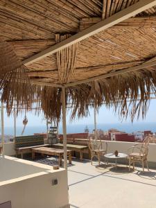 a patio with a table and chairs and a wooden umbrella at The Flow Host in Tamraght Ouzdar