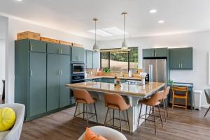 a kitchen with green cabinets and a island with bar stools at Mid-Mod Hilltop Retreat Views & Local Wildlife in Atascadero