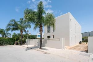 Un edificio blanco con palmeras delante. en New Villa - Rooftop Jacuzzi & Sunset Views, en Santa Bárbara de Nexe