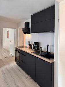 a kitchen with black cabinets and a counter top at Waldblick Hilgert - Moderne FeWo im Westerwald  +15 photos