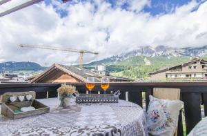 un tavolo su un balcone con 2 bicchieri di vino di Ca novella sulla Passeggiata a Cortina dʼAmpezzo