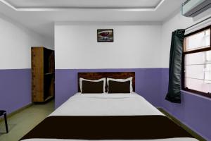 a bedroom with a bed with purple walls and a window at Hotel O P R S Elite in Surūrnagar