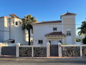 a white house with a fence and palm trees at Charming villa in Nerja in Nerja