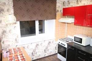 a small kitchen with red cabinets and a microwave at Шикарный ВИП в самом центре Караганды по улице Ерубаева in Karagandy