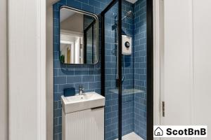 a blue tiled bathroom with a sink and a mirror at Contractor Housing - Parking - Long Stay Discounts in Aberdeen