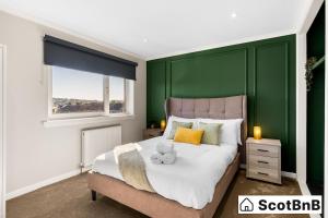 a bedroom with a large bed with a green wall at Contractor Housing - Parking - Long Stay Discounts in Aberdeen