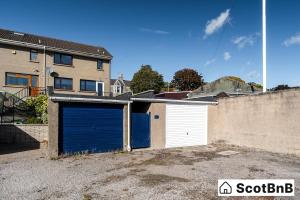 a garage with a blue door in front of a house at Contractor Housing - Parking - Long Stay Discounts in Aberdeen