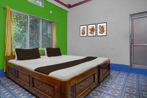 a bed in a room with a green wall at Hotel O Trinayani Homestay in Mādāri Hāt