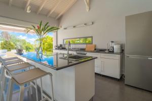 a kitchen with a sink and a counter with stools at Villa Azur in Saint-François