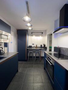 a kitchen with blue cabinets and a table in it at Coastal Lakes Mews Cottage  +1 photo