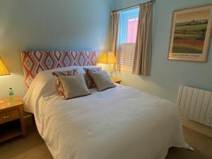 a bedroom with a white bed with two pillows at The Saddlehouse at Wykeham in Biscathorpe