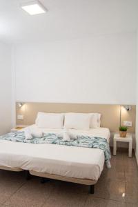 a large bed with white sheets and pillows at Le Petit Paradise in Playa de las Americas