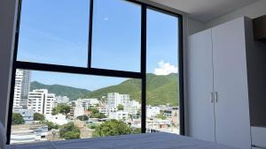 a bedroom with a large window with a view of a city at Exclusivo Aparta Suite en el Rodadero Ideal para 4 pax in Santa Marta