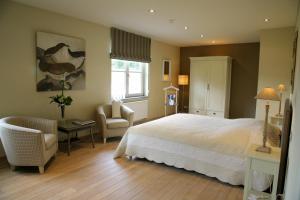 um quarto com uma cama branca e uma cadeira em B&B Vallis Dyliae em Korbeek-Dijle mais 44 fotografias