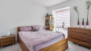 a bedroom with a bed with a wooden frame and a window at Luxurious 3BD Town house with garden in Hackbridge