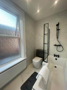 a bathroom with a tub and a toilet and a window at Seaways Holiday Home, Ocean Road, South Shields. in South Shields