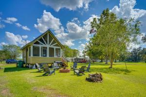 una pequeña casa amarilla con sillas y un árbol en Cozy Couples Retreat with Porch on Bayou Teche!, en New Iberia