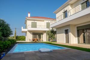 a villa with a swimming pool in front of a house at Ionian Green Villas in Preveza