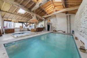 a large indoor swimming pool with a large swimming pool at Campagne Médicis Piscine, jacuzzi & sauna privés in Juré