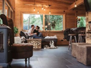 VorraRomantikchalet Fuchsbau的一对夫妇和两只狗坐在客厅的沙发上