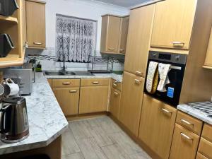 a kitchen with wooden cabinets and a stove top oven at Favourland Home in Moffat
