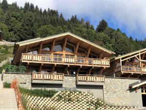 un grand bâtiment avec des balcons en bois sur une montagne dans l'établissement Chalet de luxe avec jacuzzi, sauna, parking et WIFI aux Gets - FR-1-598-19, aux Gets