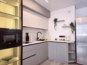 a kitchen with white cabinets and a black microwave at Belvedere Apart 2, parking in Ivano-Frankivsʼk