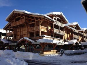 a large wooden building covered in snow at Confortable T4, terrasse, parking et Wi-Fi, au centre et proche pistes - FR-1-598-129 in Les Gets