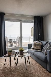 sala de estar con sofá y mesas frente a una ventana en Let's Go Nieuwpoort, en Nieuwpoort