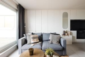 a living room with a blue couch and a table at Seaview Penthouse with Terrace Nieuwpoort in Nieuwpoort