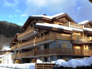 a large wooden building with snow on it at Appartement montagnard 4* cosy, 2 ch, 6 pers - FR-1-598-6 in Les Gets