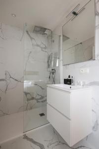 Un baño blanco con ducha y lavabo. en Let's Go Nieuwpoort, en Nieuwpoort