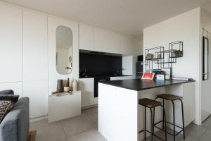 a kitchen with white cabinets and a black counter top at Seaview Penthouse with Terrace Nieuwpoort in Nieuwpoort