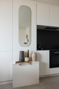 cocina con armarios blancos y espejo en Let's Go Nieuwpoort, en Nieuwpoort