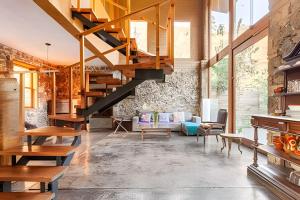 a living room with a wooden staircase and a stone wall at Cabañas de la Insolente in Tepoztlán