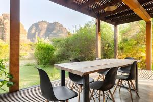 a wooden table and chairs on a porch with a view of mountains at Cabañas de la Insolente in Tepoztlán