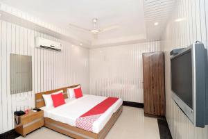 Un dormitorio con una cama y un televisor de pantalla plana. en Hotel O Le Bon Ton, en Ludhiana