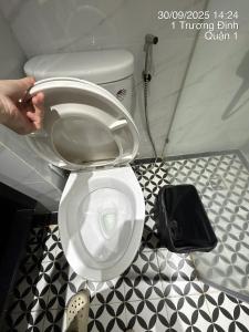a person holding the lid of a toilet in a bathroom at Balack Hutsa Hotesl 7 in Ho Chi Minh City