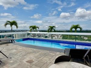 a swimming pool on the roof of a building with palm trees at Manaus Hotéis Millenium - Flat 804 in Manaus