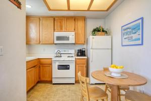a kitchen with a table and a white refrigerator at Pacific Plaza #109 - Seaside Setting - 1BdrmUp-K-QSofa in Oceano